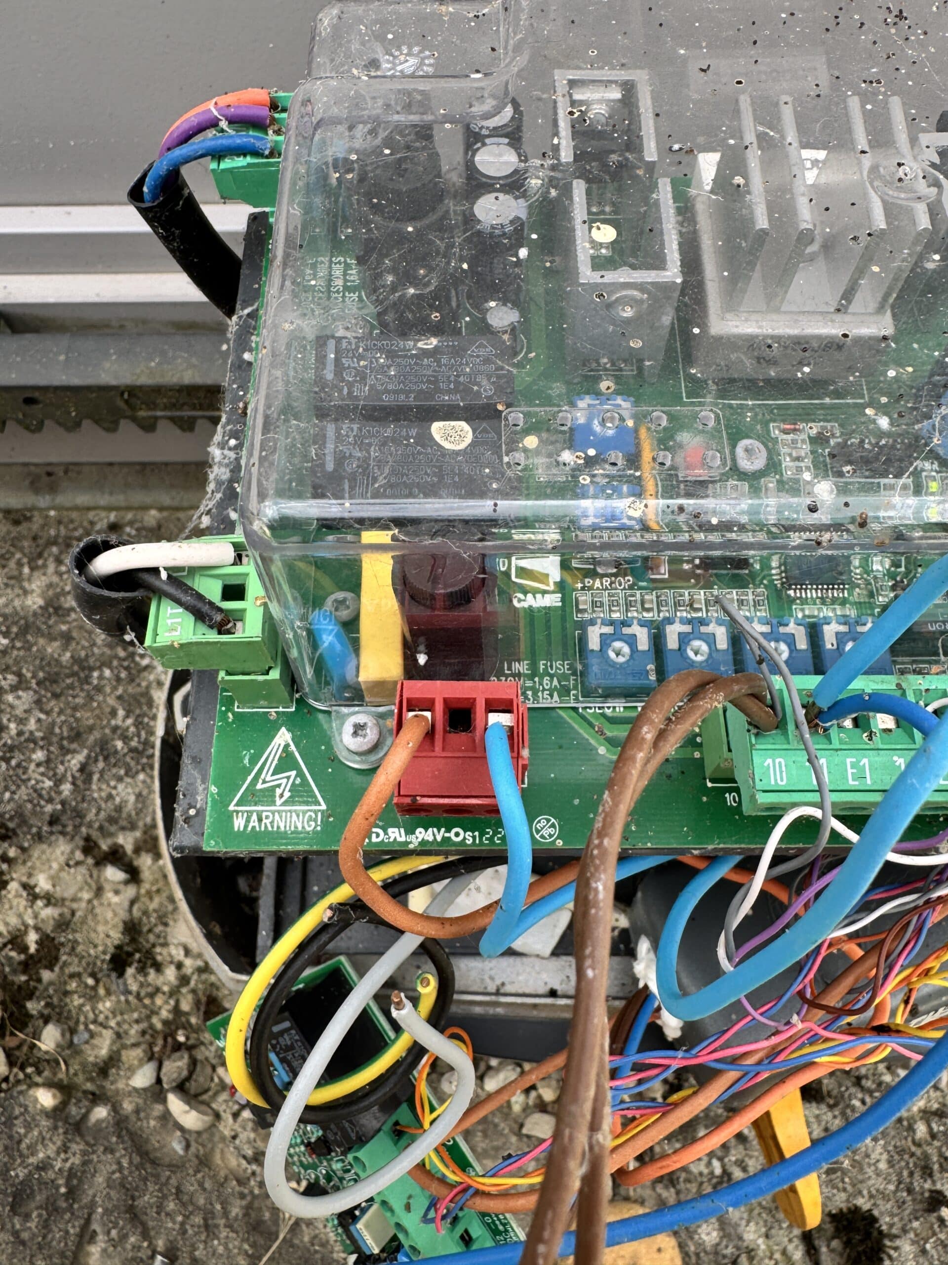Platine électronique CAME poussiéreuse avec fils multicolores et connecteur rouge. Texte: WARNING!, LINE FUSE 1.6A-F, 3.15A-L.