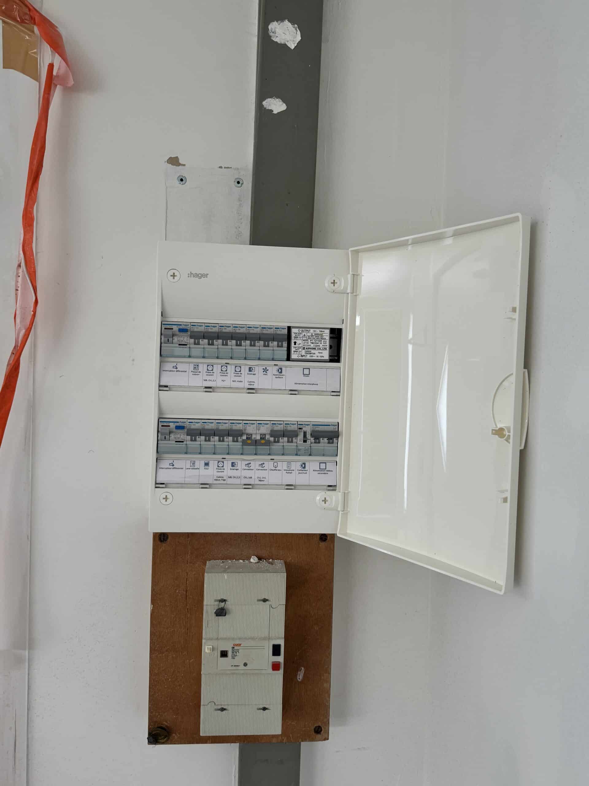 Tableau électrique Hager ouvert, montrant disjoncteurs étiquetés et module Aiphone. Disjoncteur principal Gindy DB sur support bois.